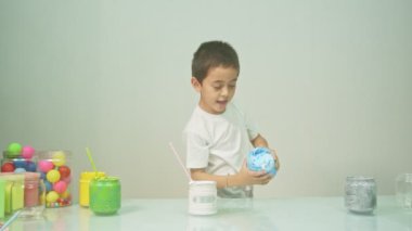 Bir çocuk sevinçle yeni bir rengi karıştırıyordu. Çocuk okulda renkleri karıştırıyordu, çocukların yönettiği Montessori metodu. Yüksek kaliteli 4K video stüdyosu. renkli arkaplan.