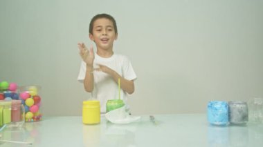 Bir çocuk sevinçle yeni bir rengi karıştırıyordu. Çocuk okulda renkleri karıştırıyordu, çocukların yönettiği Montessori metodu. Yüksek kaliteli 4K video stüdyosu. renkli arkaplan.