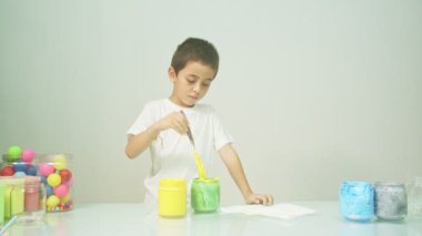 Bir çocuk sevinçle yeni bir rengi karıştırıyordu. Çocuk okulda renkleri karıştırıyordu, çocukların yönettiği Montessori metodu. Yüksek kaliteli 4K video stüdyosu. renkli arkaplan.