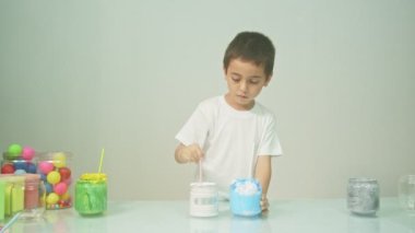 Bir çocuk sevinçle yeni bir rengi karıştırıyordu. Çocuk okulda renkleri karıştırıyordu, çocukların yönettiği Montessori metodu. Yüksek kaliteli 4K video stüdyosu. renkli arkaplan.