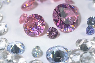 Beyaz arka planda, beyaz elmasların arasına yerleştirilmiş bir grup pembe elmas.