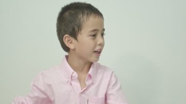Pembe tişört giyen bir çocuk dizüstü bilgisayarın mutluluğunu izliyordu. Stüdyo portresi, beyaz arkaplan konsepti.. 