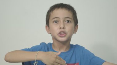Mavi gömlek giyen sevimli çocuk sütün tadını bilmek ve sütün tadını açıklamak için sütün tadına baktı. Stüdyo portresi, beyaz arkaplanlı konsept sağlık.  