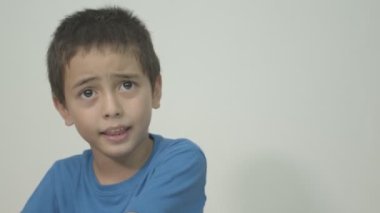 Mavi gömlek giyen sevimli çocuk sütün tadını bilmek ve sütün tadını açıklamak için sütün tadına baktı. Stüdyo portresi, beyaz arkaplanlı konsept sağlık.  