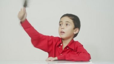 Kırmızı uzun kollu gömlekli küçük çocuk oturdu, saçını taradı ve sürekli konuştu. Stüdyo beyaz arka plan çekti. Yüksek kalite video 4K.. 