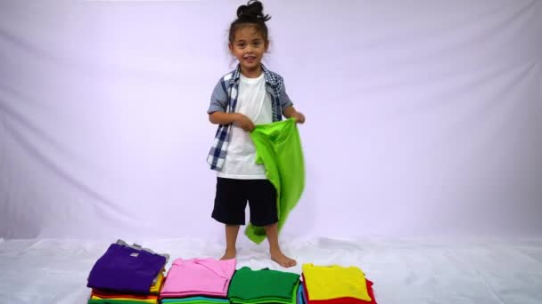 Мальчик Клетчатой Рубашке Держащий Зеленую Рубашку Раскачивающуюся Куче Разноцветных Рубашек — стоковое видео