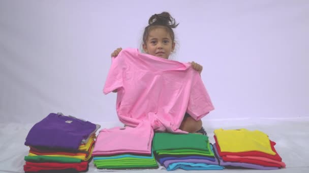 Мальчик Клетчатой Рубашке Держащий Зеленую Рубашку Раскачивающуюся Куче Разноцветных Рубашек — стоковое видео