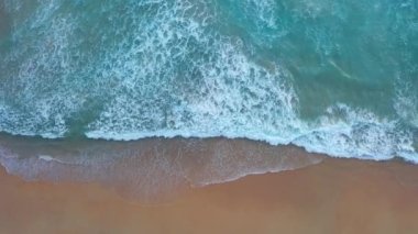 Beyaz Phuket kumsalında hava manzaralı deniz dalgaları pürüzsüz bir döngü oluşturuyor. Gün batımında tropikal bir kumlu plajda yürü. Mavi deniz ve temiz kum manzarası. Cennet plajı.