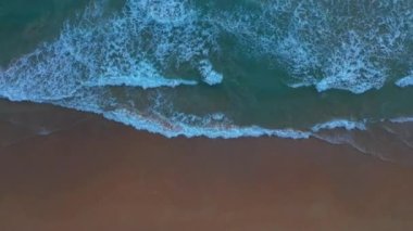 Beyaz Phuket kumsalında hava manzaralı deniz dalgaları pürüzsüz bir döngü oluşturuyor. Gün batımında dalga dalga kıyıya doğru sürüklendi. Mavi deniz ve temiz kum manzarası. Cennet plajı.