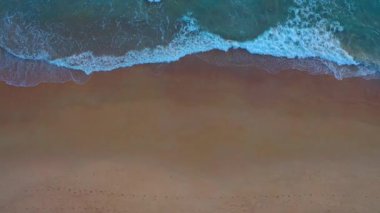 Beyaz Phuket kumsalında hava manzaralı deniz dalgaları pürüzsüz bir döngü oluşturuyor. Gün batımında dalga dalga kıyıya doğru sürüklendi. Mavi deniz ve temiz kum manzarası. Cennet plajı.