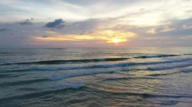 Beyaz Phuket kumsalında hava manzaralı deniz dalgaları pürüzsüz bir döngü oluşturuyor. Gün batımında dalga dalga kıyıya doğru sürüklendi. Mavi deniz ve temiz kum manzarası. Cennet plajı.