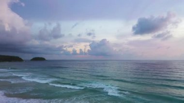 Beyaz Phuket kumsalında hava manzaralı deniz dalgaları pürüzsüz bir döngü oluşturuyor. Gün batımında dalga dalga kıyıya doğru sürüklendi. Mavi deniz ve temiz kum manzarası. Cennet plajı.