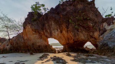 time lapse sunset in the hole of rock piercing Hin Thalu in Buffalo Bay Koh Phayam Ranong Province.Another charm of Koh Phayam on the beach has a lot of unusual rockThat has been eroded into the cavity like the arch with a hole 