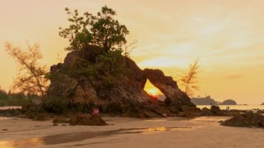 time lapse sunset in the hole of rock piercing Hin Thalu in Buffalo Bay Koh Phayam Ranong Province.Another charm of Koh Phayam on the beach has a lot of unusual rockThat has been eroded into the cavity like the arch with a hole 