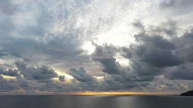 Arka planda siluetler olan turuncu gün batımı ışığı altında güzel bir sahil. Kumda dalgalar kopuyor, hava manzarası, Karon sahili Phuket Tayland.