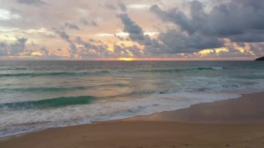 Arka planda siluetler olan turuncu gün batımı ışığı altında güzel bir sahil. Kumda dalgalar kopuyor, hava manzarası, Karon sahili Phuket Tayland.