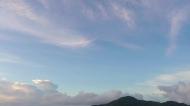 Dağların tepesindeki mavi gökyüzünde beyaz bulutlar.