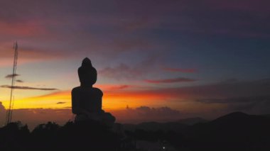 Hava manzaralı gün batımı. Yağmur bulutları yazın hareket ediyor. Güzel siluet Phuket Büyük Buda tepede. Turistlerin gelmesi için bir teşvik daha. Seyahat ve ibadet konsepti için 4k video
