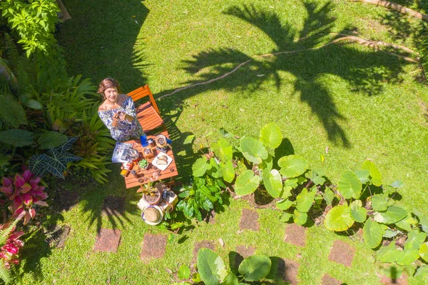 A woman holding a glass of hot coffee in green garden. A woman relax in green garden with coffee set on wooden table. green garden background.