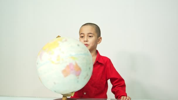 Ein Junge Mit Skinhead Roten Hemd Dreht Die Weltkugel Ein — Stockvideo
