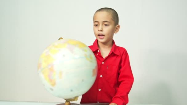 Ein Junge Mit Skinhead Roten Hemd Dreht Die Weltkugel Ein — Stockvideo