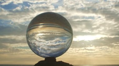 Plaj videosu 4K 'nin yanındaki kereste üzerinde kristal kürenin içinde gün batımını hızlandırıyor. Doğa videosu: Yüksek kaliteli görüntüler doğada ve seyahat konseptinde günden geceye hızlandırılır.