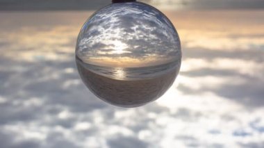 Plaj videosu 4K 'nin yanındaki kereste üzerinde kristal kürenin içinde gün batımını hızlandırıyor. Doğa videosu: Yüksek kaliteli görüntüler doğada ve seyahat konseptinde günden geceye hızlandırılır.