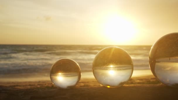 3个水晶球内的金色落日放置在海滩边的木头上 美丽的大自然在海边的水晶球里 独特而富有创意的旅行和大自然的创意视频4K片断 — 图库视频影像