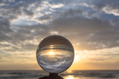 Güzel bulut ve altın gün batımı kristal küre içinde plajın yanındaki bir kereste üzerine yerleştirilmiş