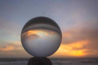 Güzel bulut ve altın gün batımı kristal küre içinde plajın yanındaki bir kereste üzerine yerleştirilmiş