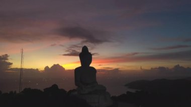 Alacakaranlık arka planında Phuket Büyük Buda renkli gökyüzünün hava manzarası silueti. Turistleri ziyaret etmeleri için bir teşvik daha. Seyahat ve ibadet konsepti için 4k video.