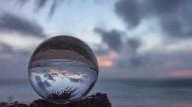 Kırmızı günbatımında bir dalda hızlandırılmış kristal küre 