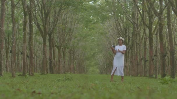 드레스를 여성은 카메라를 사용하여 고무나무 배경의 사진을 촬영한다 고품질 비디오 — 비디오
