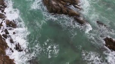 Sahilin yanındaki kayaya çarpan hava dalgaları. Kayadaki turkuaz denizde beyaz kabarcık dalgaları. yaratıcı doğa ve seyahat kavramı. 
