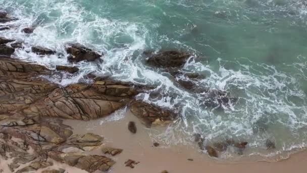 ビーチの横の岩の上に空中のトップビュー波 岩の上のターコイズブルーの海の白い泡波 創造的な自然と旅のコンセプト — ストック動画