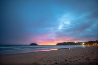 Kata Beach Phuket 'teki Pu adasının arkasında güzel bir günbatımı. Birçok turist gün batımında plajda dinlenir.