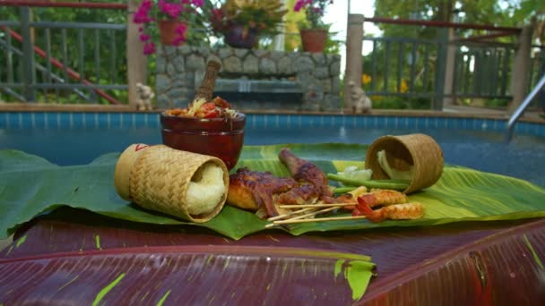 木瓜沙拉 烤鸡肉和烤虾仁放在斑斑的香蕉叶盘上 背景是红色的黄绿色斑点香蕉叶 食品和餐馆概念 — 图库视频影像