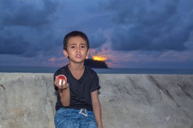 Gün batımında Kata Sahili 'ndeki Phuket Tayland' da kristal küreyi elinde tutan bir çocuk. Mutlu çocuğun gülümseyen yüzü konsepti..