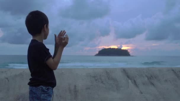 在泰国卡塔海滩 一个男孩在波障旁拿着一个水晶球 夕阳西下的云彩 放松的概念 — 图库视频影像