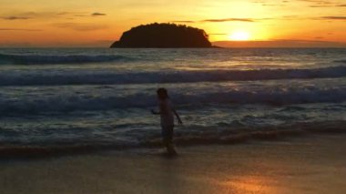 Altın gün batımında plajda oynayan bir çocuk. Cennet sahili mavi denizi ve temiz kumsal manzarası. komik çocuk ve seyahat konsepti.