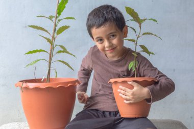 Mutlu bir çocuk Kratom ağacı fidanlarıyla eğlenir..
