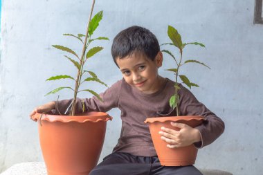Mutlu bir çocuk Kratom ağacı fidanlarıyla eğlenir..