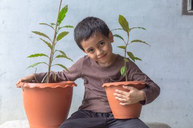 Mutlu bir çocuk Kratom ağacı fidanlarıyla eğlenir..