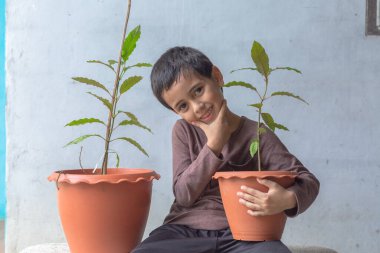 Mutlu bir çocuk Kratom ağacı fidanlarıyla eğlenir..