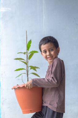 Mutlu bir çocuk Kratom ağacı fidanlarıyla eğlenir..