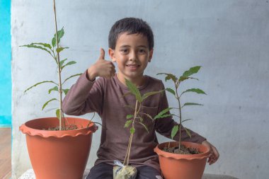 Mutlu bir çocuk Kratom ağacı fidanlarıyla eğlenir..