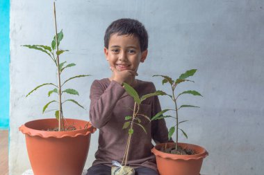 Mutlu bir çocuk Kratom ağacı fidanlarıyla eğlenir..