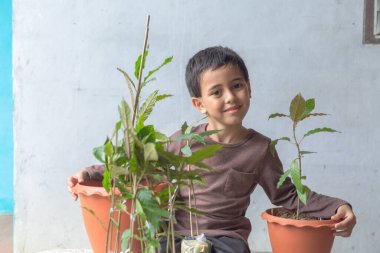 Mutlu bir çocuk Kratom ağacı fidanlarıyla eğlenir..