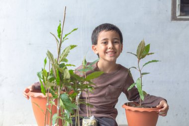 Mutlu bir çocuk Kratom ağacı fidanlarıyla eğlenir..