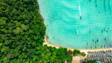 Morgan Köyü 'nün Surin Adası' ndaki doğal güzelliklere gizlenmiş havadan görüntüsü. Kıyı şeridi boyunca yemyeşil ormanlarla çevrili küçük kulübeler. Balıkçı tekneleri turkuaz sularda demirli..    